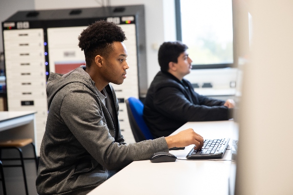 Two students sat in front of monitors typing