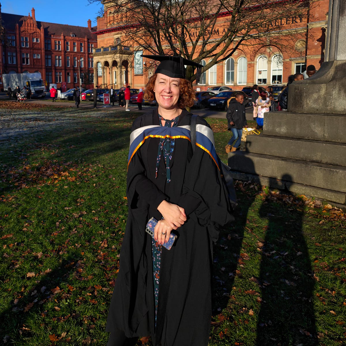 Erica Boardman in a graduation cap and gown outside Salford Museum