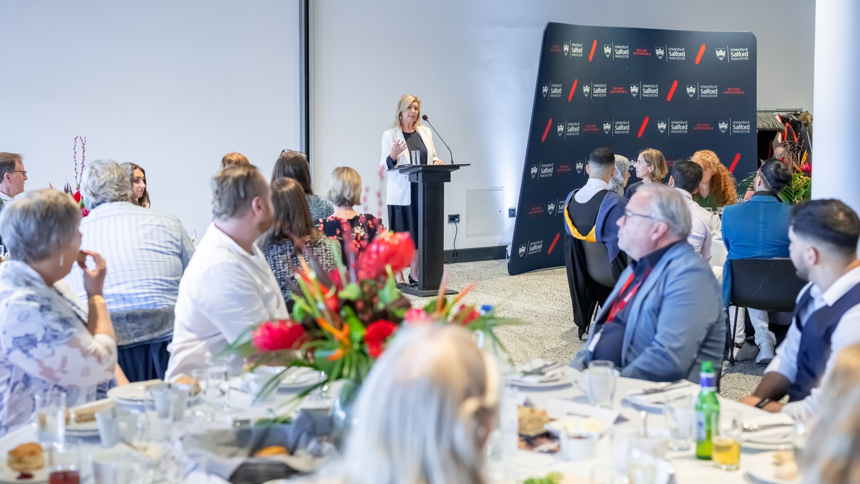 Lucy meacock addressing the room full of seated guests in the the lowry at The Donor funded scholarships graduation celebration