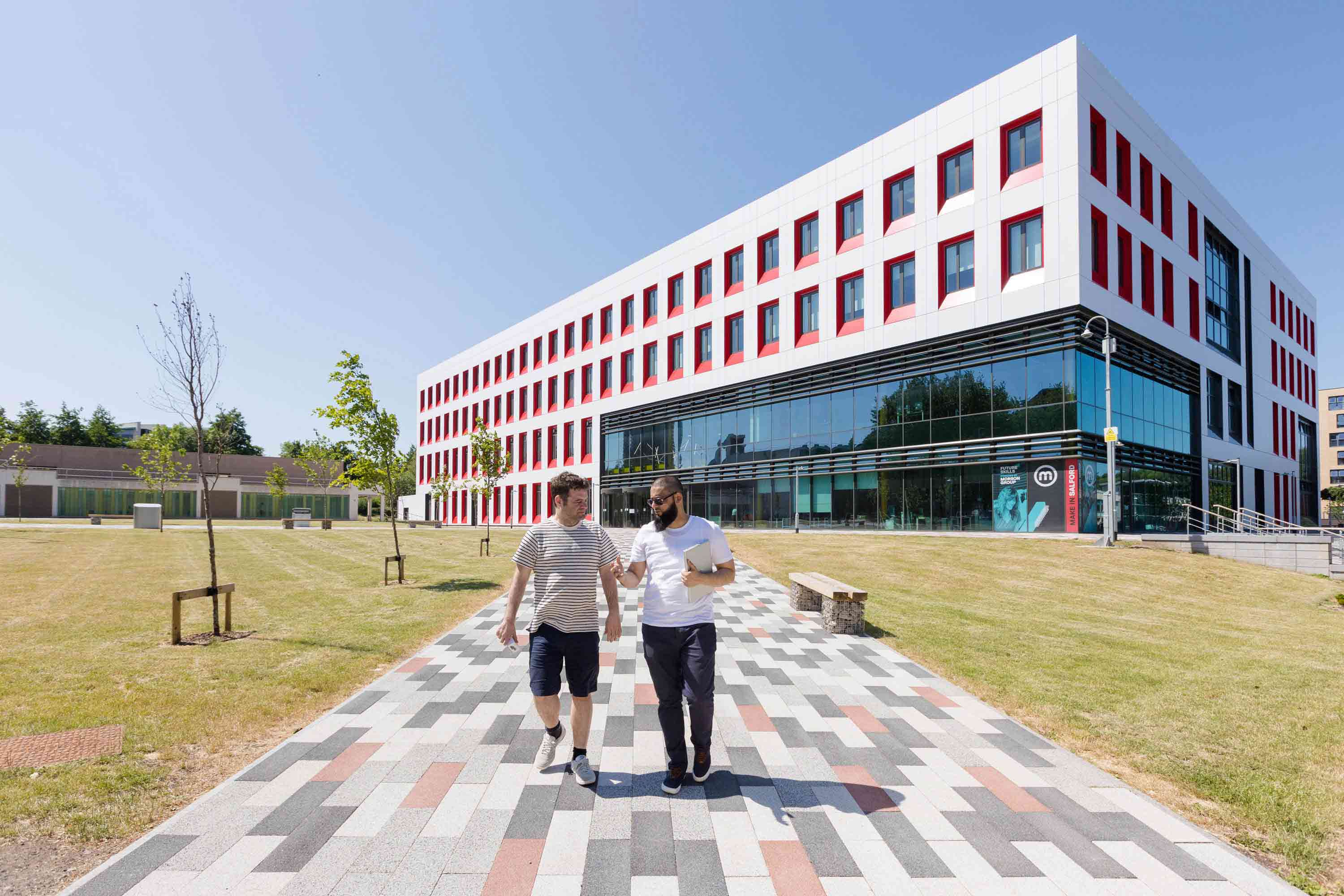 Two students walking outside the Science, Engineering & Environment (SEE) Building, University of Salford