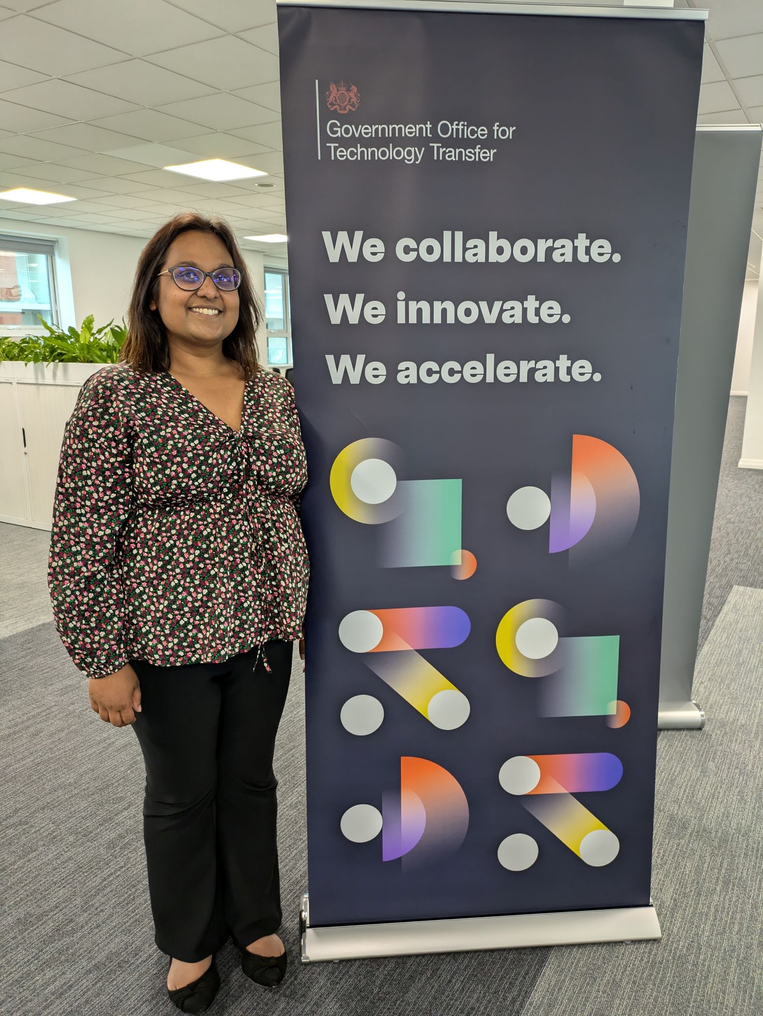 Sarwat Howe stood next to a Government Office for Technology Transfer roller banner