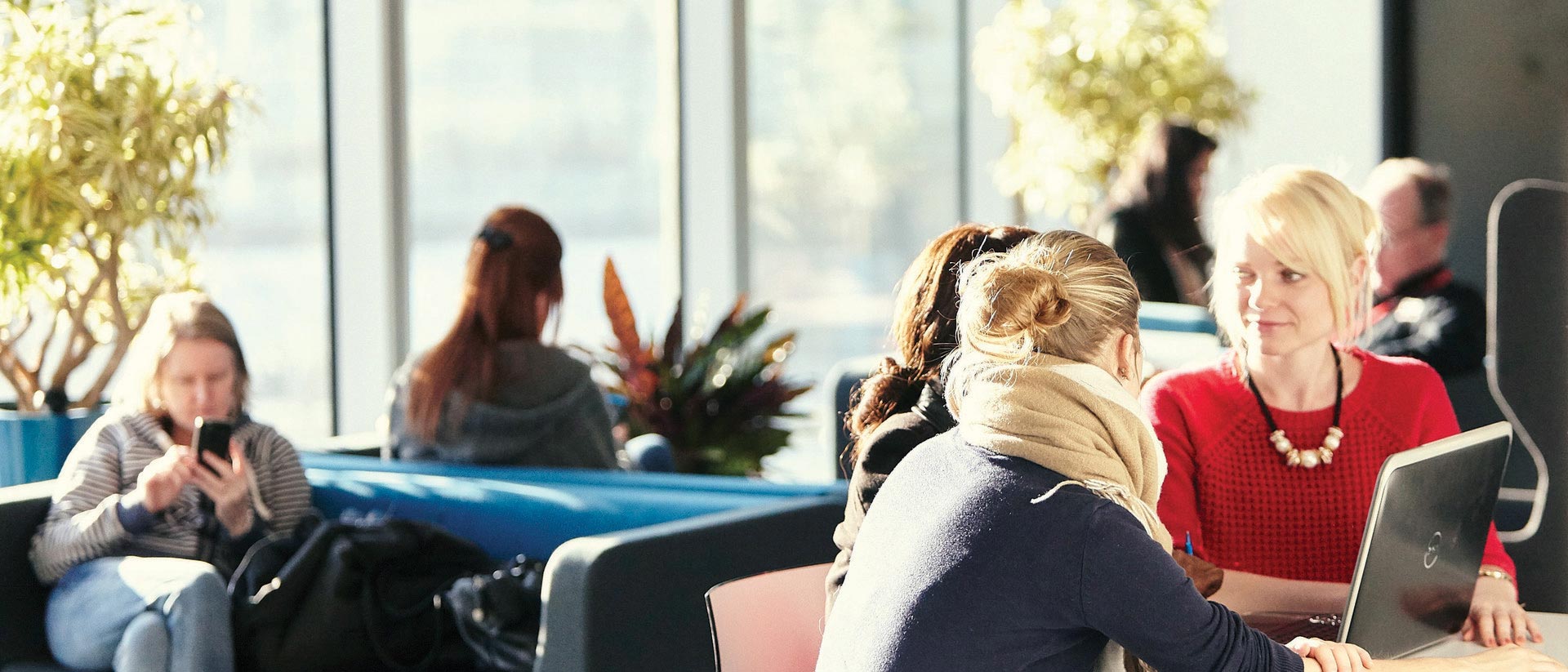 Three people discussing around a laptop in a common area