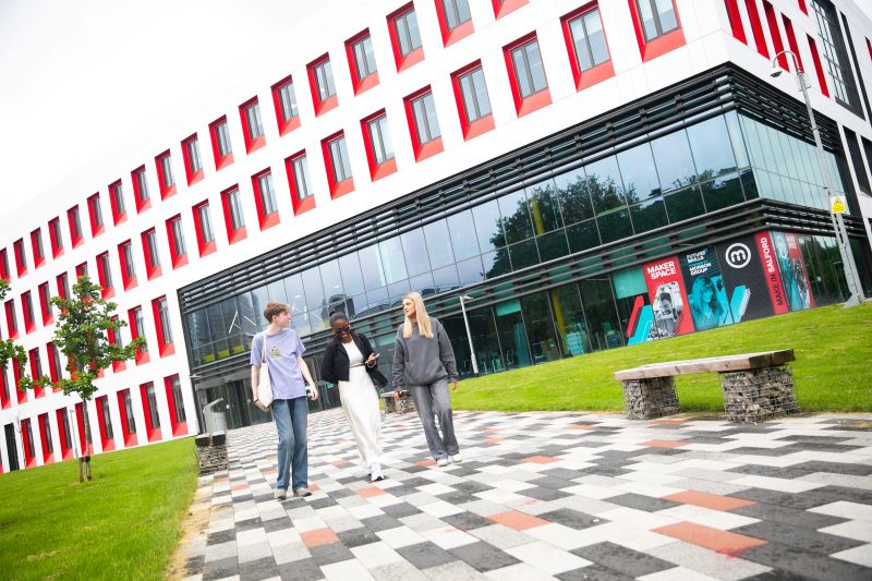 Three students walking outside the SEE Building at the University of Salford