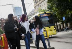 Students in Manchester city centre with a tram behind