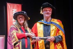Paul Stewart with Professor Helen Marshall OBE recieving honorary graduate, posing for a photo in graduation attire. 