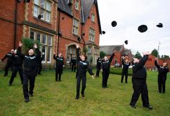 A group of public services apprentices celebrating by throwing their hats in the air