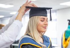 Graduate robing session, adjusting a hat for a persons head