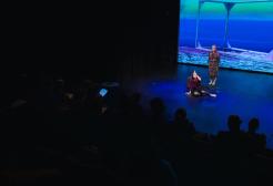 Two performers on stage in front of an audience in the Development Lab