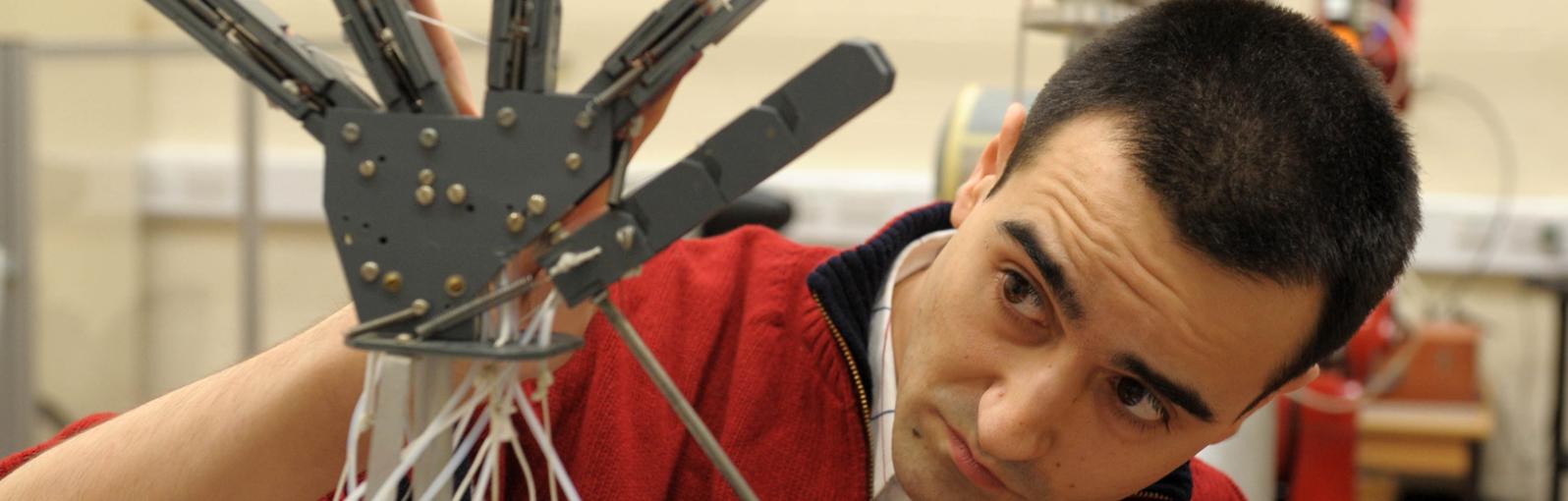 Student in robotics lab operating a robotic hand