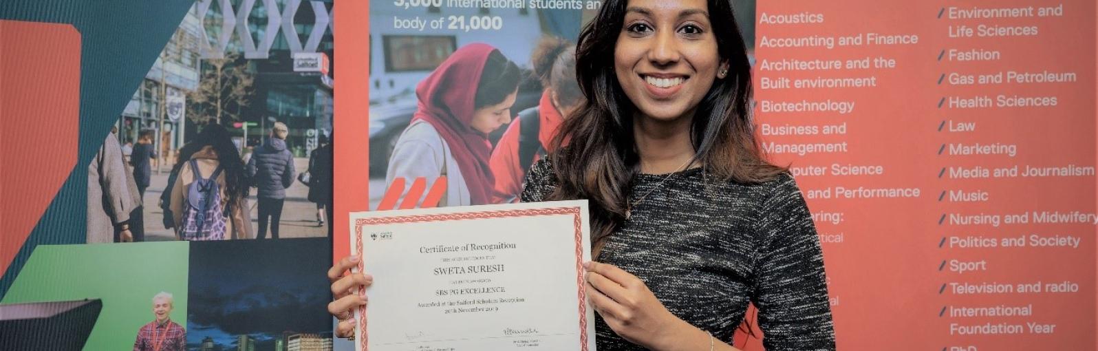 Sweta Suresh holding her SBS PG Excellence Certificate of Recognition