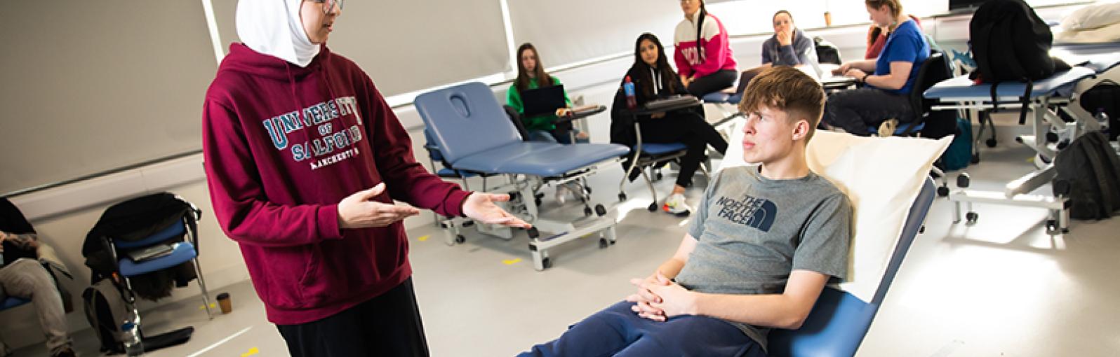 Group of Physiotherapy students engaging in a practical session and using a plynth room to examine each other at the University of Salford 