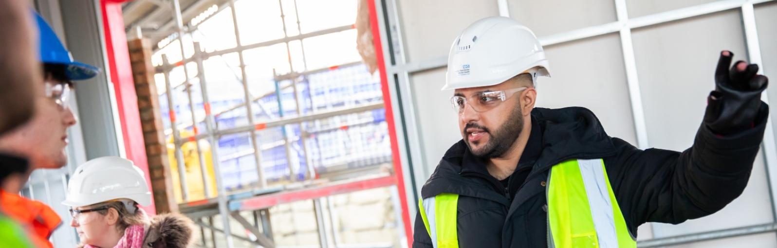 A male student on a construction site giving instructions
