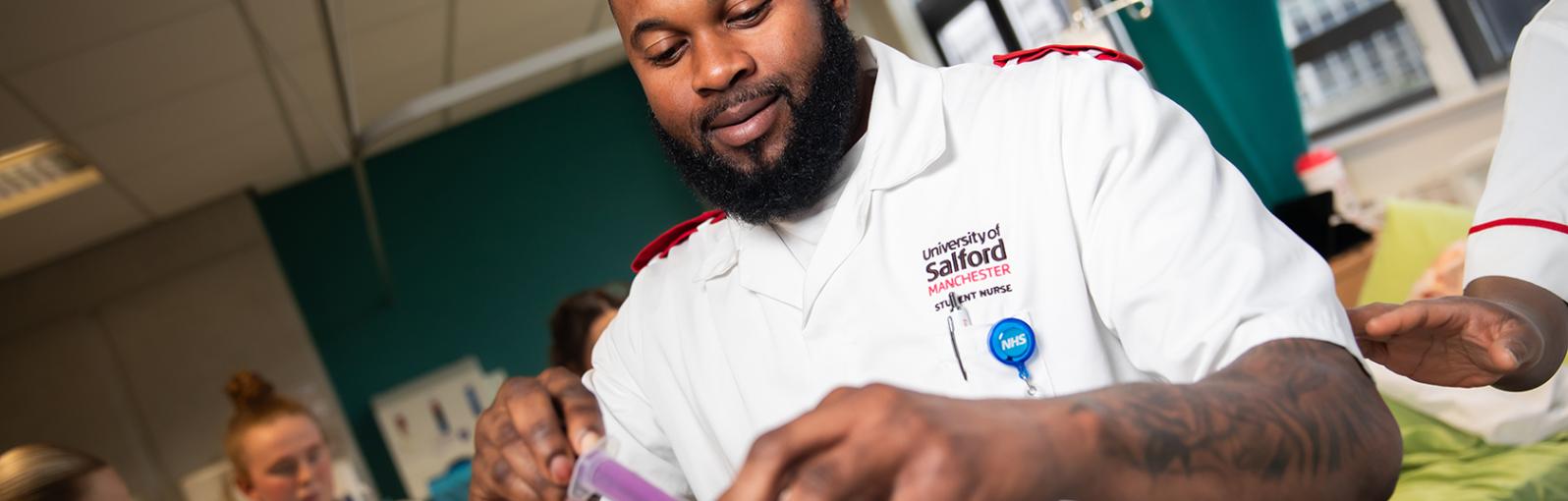 Nursing student uses a syringe to measure out medicine from a bottle