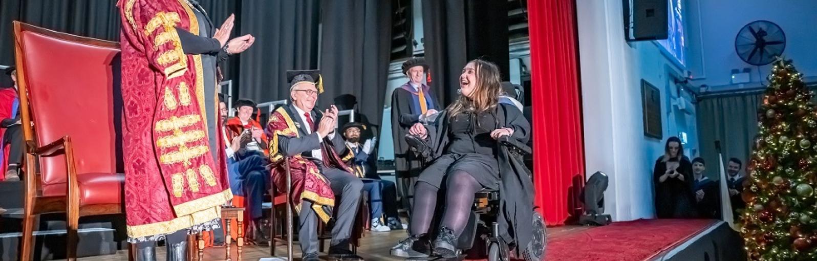 Graduate crossing the stage in a wheelchair