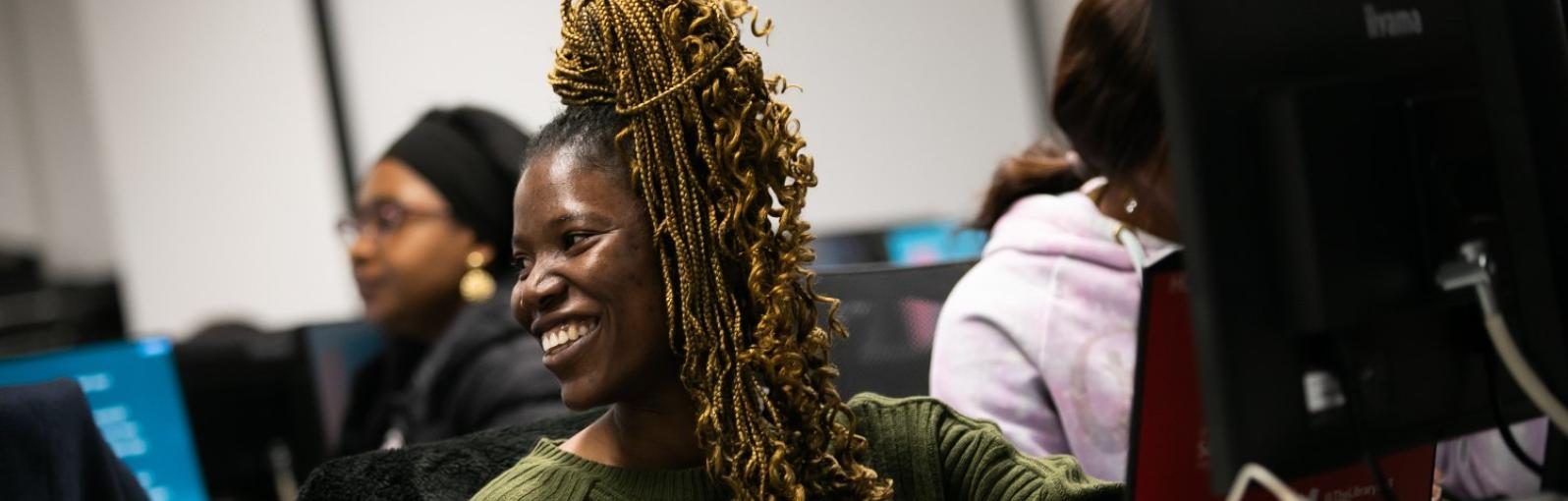 a smiling student looking to the side in a computer suite