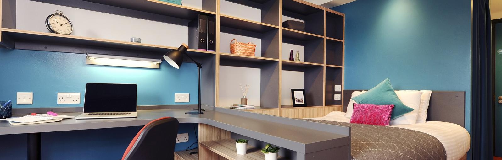 Student bedroom with blue walls, bed, built-in shelving and desk