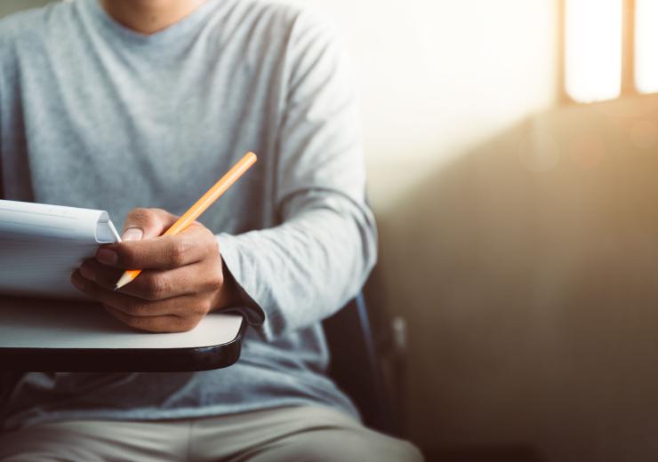 Male student holding a pen and paper 