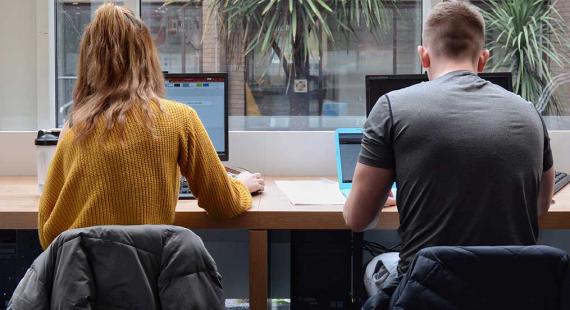 Two students work online in a library