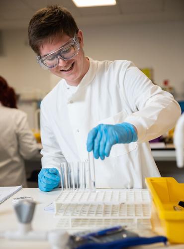 Biomedical Science apprentice in a lab holding equipment 