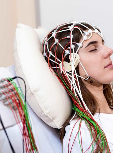 Woman lying in bed wearing EEG equipment 