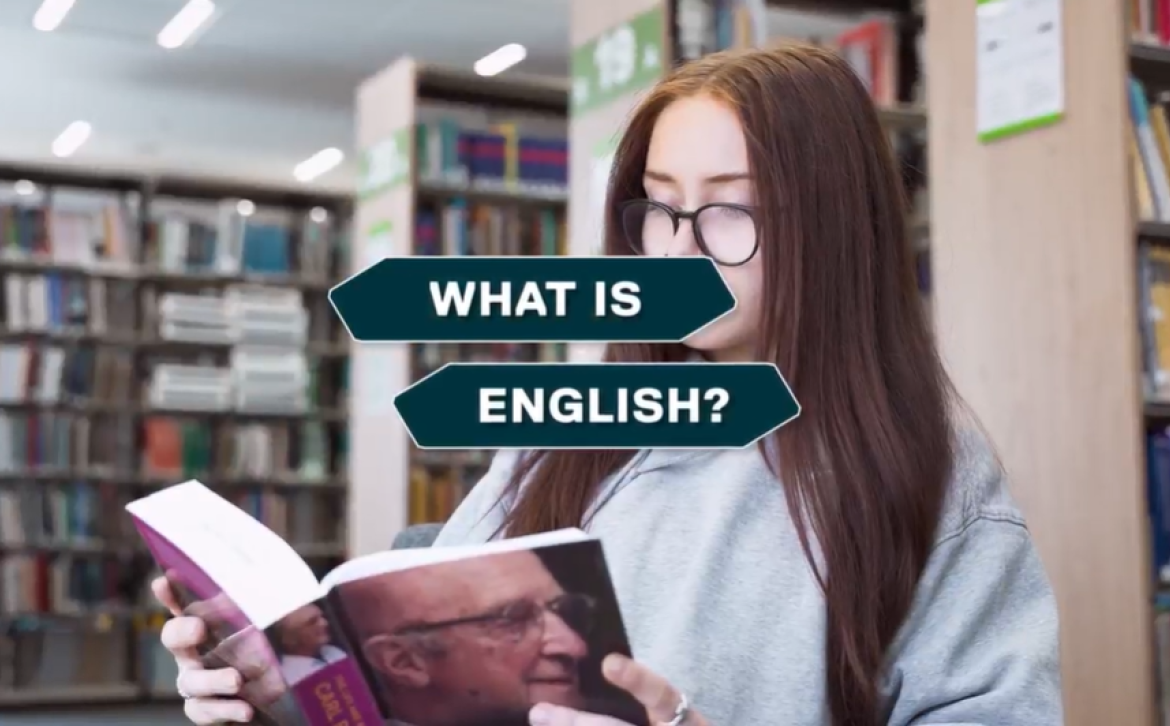 Student sitting down reading a book, with an overlay on screen that says 'What is English?'